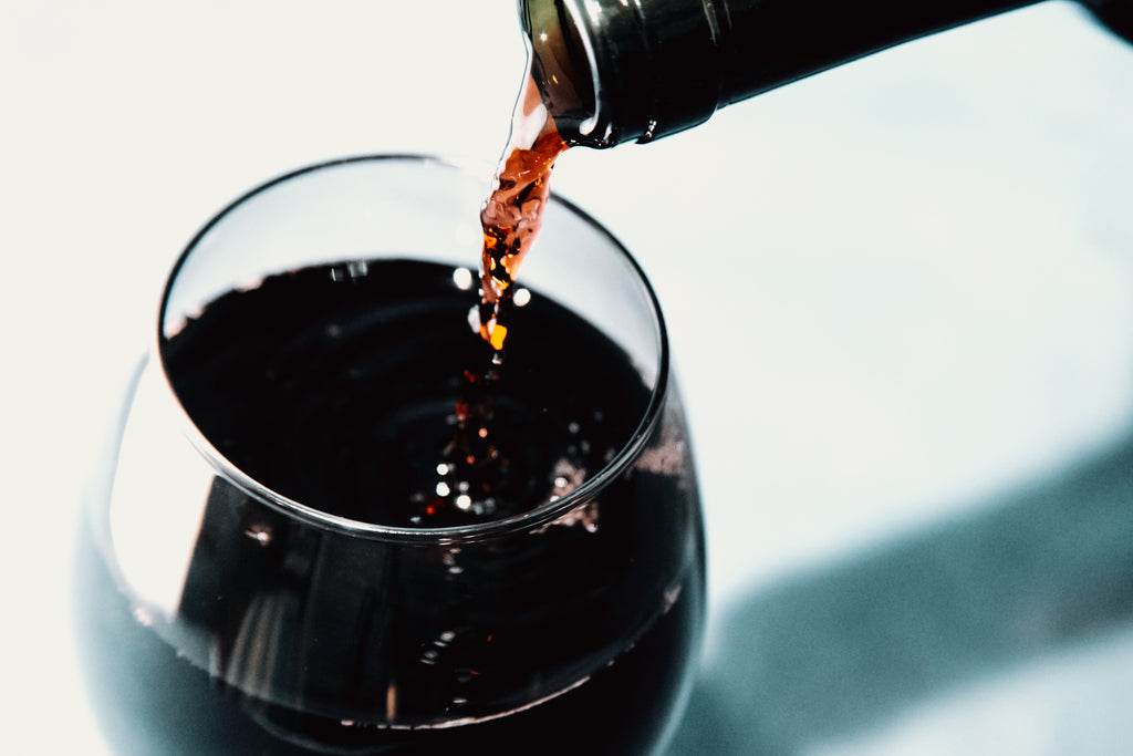Picture of red wine being poured into a wine glass.